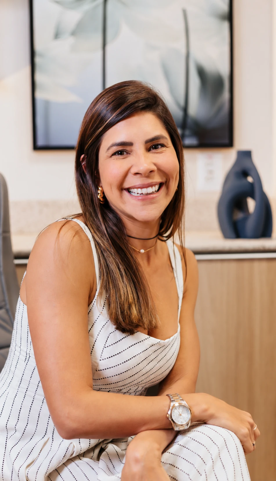 Natália Amorim sentada e sorrindo em um retrato profissional